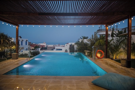 Una piscina al aire libre, sombrillas, sillones reclinables de piscina