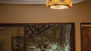 A modern living room with a large orange armchair, a decorative wall with a tree and plants, and a wooden cabinet. - Dar Lina  (El Haouaria)