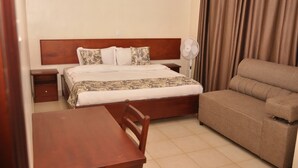 Una habitación de hotel con una cama, un sofá, una mesa y una mesita de noche.