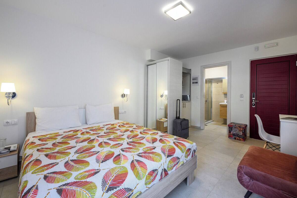 Ein Hotelzimmer mit Bett, Nachttischen, Schreibtisch, Stuhl, Kleiderschrank und Bad.