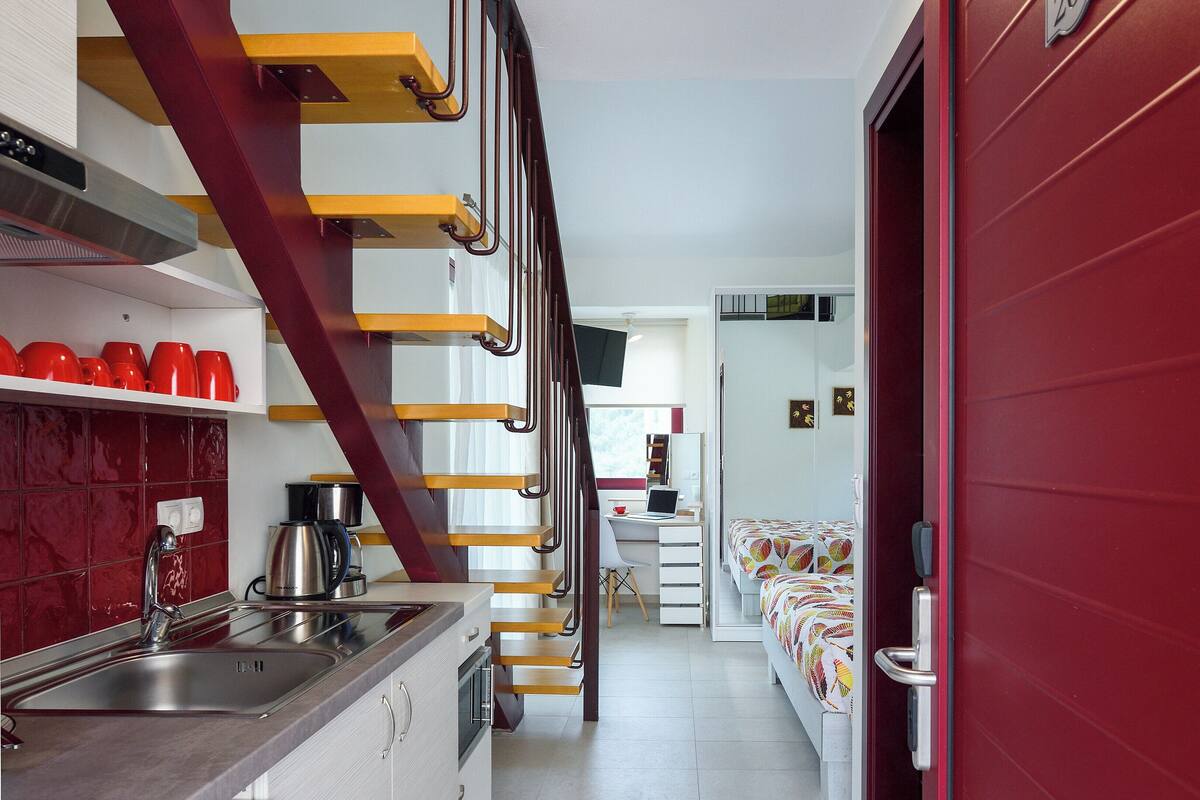 Eine moderne Küche mit einer roten Treppe, einem Spülbecken und einer Kaffeemaschine.