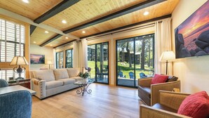 A spacious living room with a wooden ceiling, large windows, and a view of the outdoors. - Million Dollar Views of Lake Tahoe - #13 (Kings Beach)