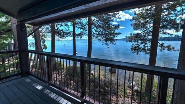 A wooden deck with a railing overlooking a body of water and trees. - Serene Lakefront Townhouse with Breathtaking Views at Brockway Springs- #4 (Kings Beach)