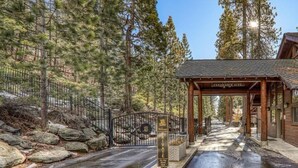 A private entrance gate with a wooden archway labeled "Clearance Gate" leading to a building with a sloped roof. - Newly Remodeled Lake-View retreat #21 (Kings Beach)