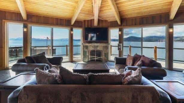 A cozy room with a fireplace, large windows, and a view of the water. - Newly Remodeled Lake-View retreat #21 (Kings Beach)
