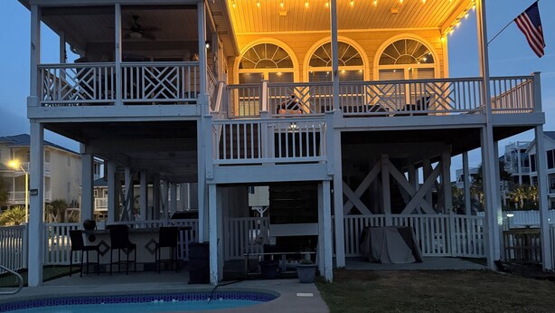 A two-story house with a balcony, a pool, and a flag.
