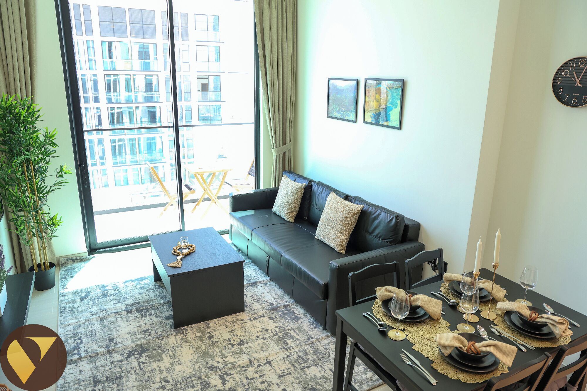 A modern living room with a black leather sofa, a coffee table, and a dining area set for six.