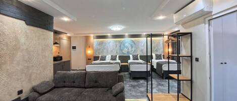 A hotel room with a sofa, two beds, a wooden table, and a marble floor.