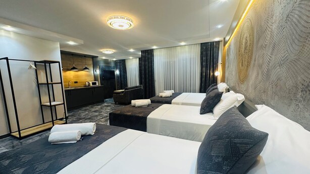 Ein Hotelzimmer mit zwei Betten, einer Couch, einem Schreibtisch und einer Küchenzeile.