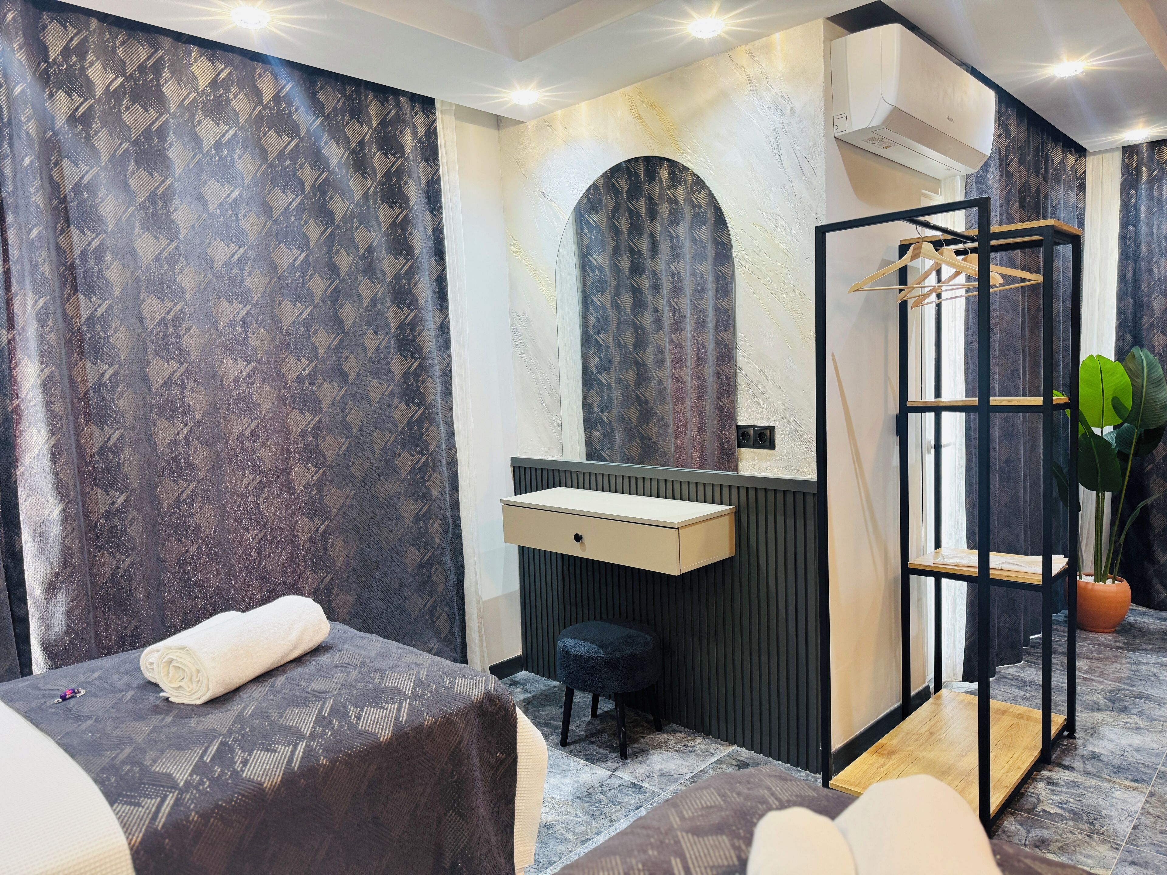 Una habitación de hotel moderna con cama, un escritorio pequeño, un espejo y una planta.