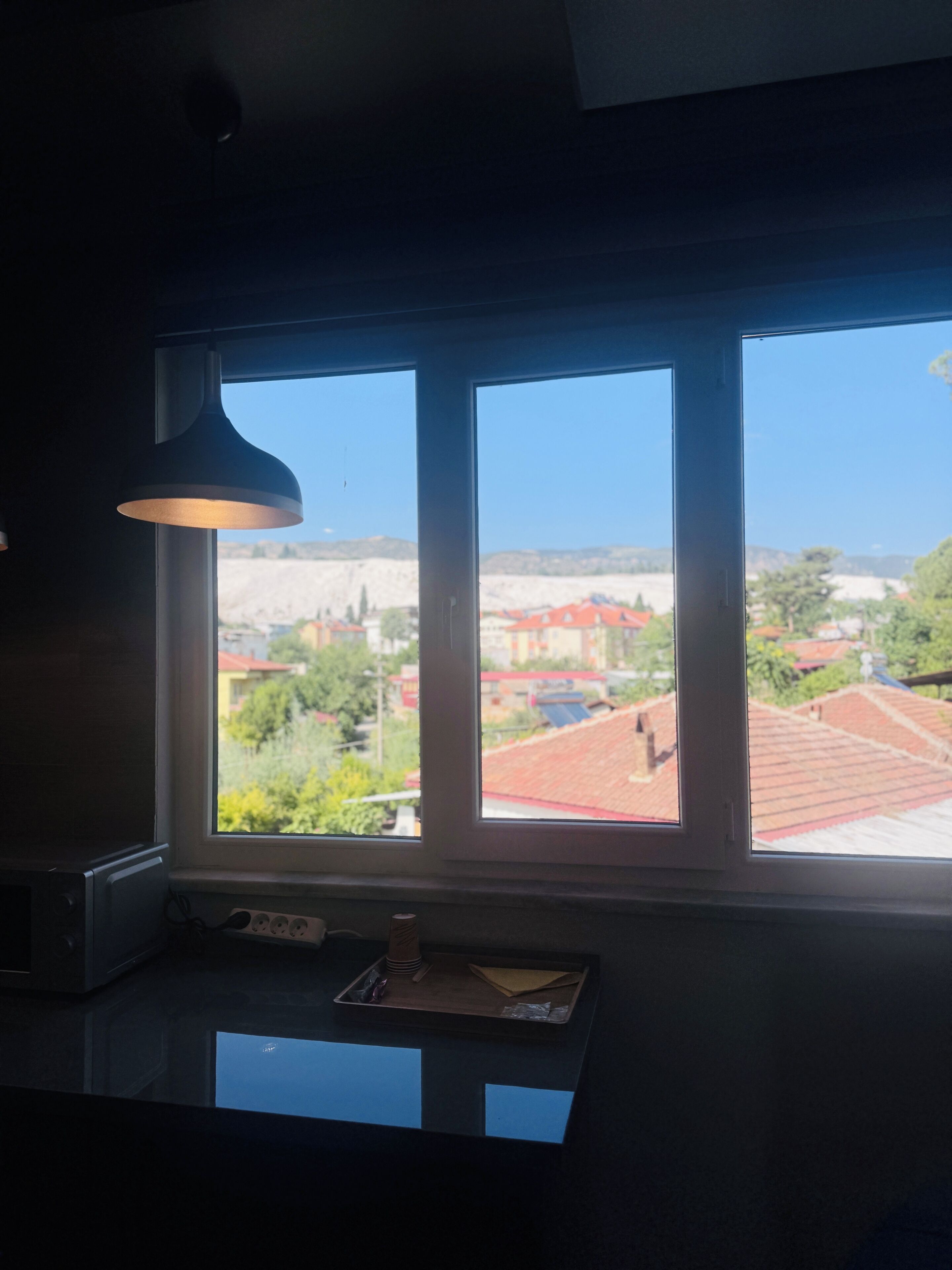 A kitchen with a large window overlooking a residential area.
