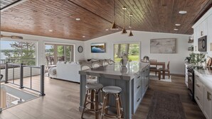 Une cuisine spacieuse dotée d’un grand îlot central, d’un plafond en bois et d’appareils électroménagers modernes.