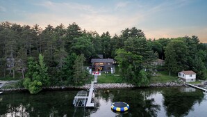 Une maison au bord du lac, dotée d’un quai, et entourée d’une forêt dense.