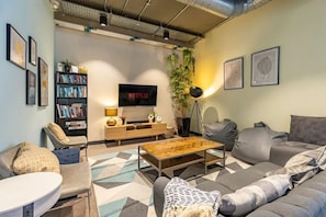 A modern living room with a sofa, armchair, coffee table, bookshelf, TV, and decorative plants. - For Students Only Curraheen Point  (Cork)