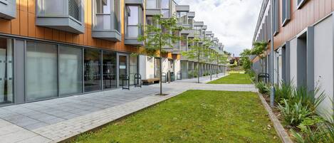 A modern apartment building with a long, straight driveway and a well-maintained lawn.