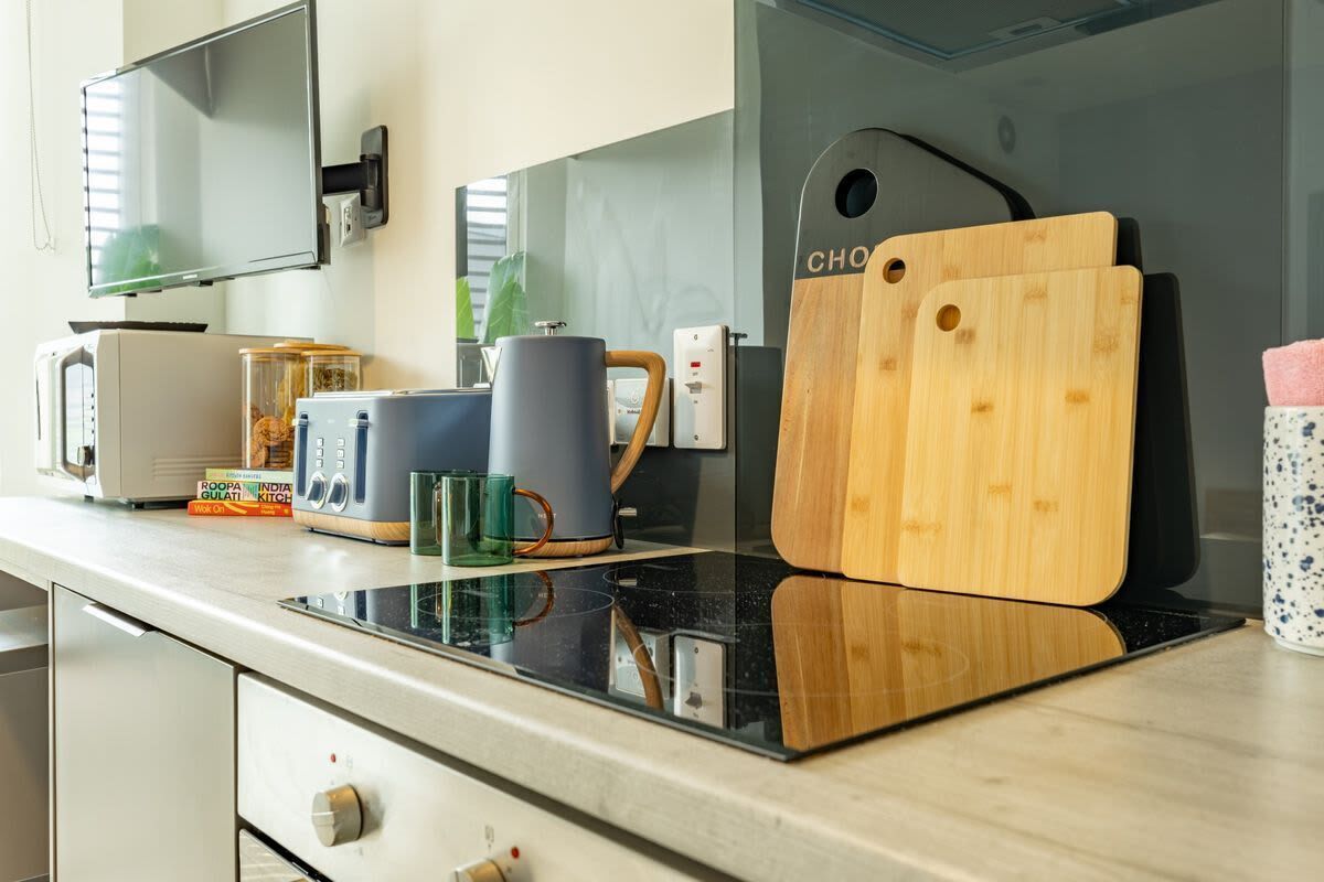 Una encimera de cocina con microondas, cafetera, tostadora y tabla de cortar.