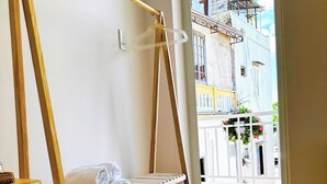 A room with a wooden bunk bed, a small wooden table with a basket, and a shelf with folded towels. - Tom's Homestay Hue (Hue)