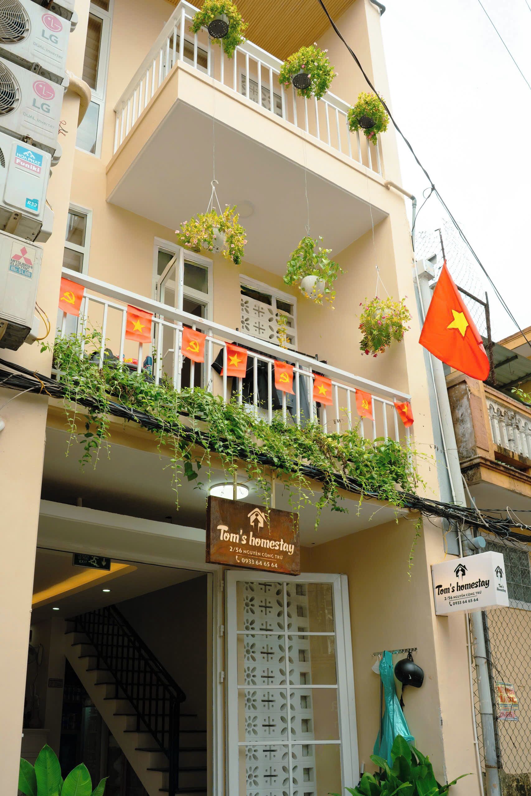 A building with a sign for 'Tom's Homestay' and a Vietnamese flag.