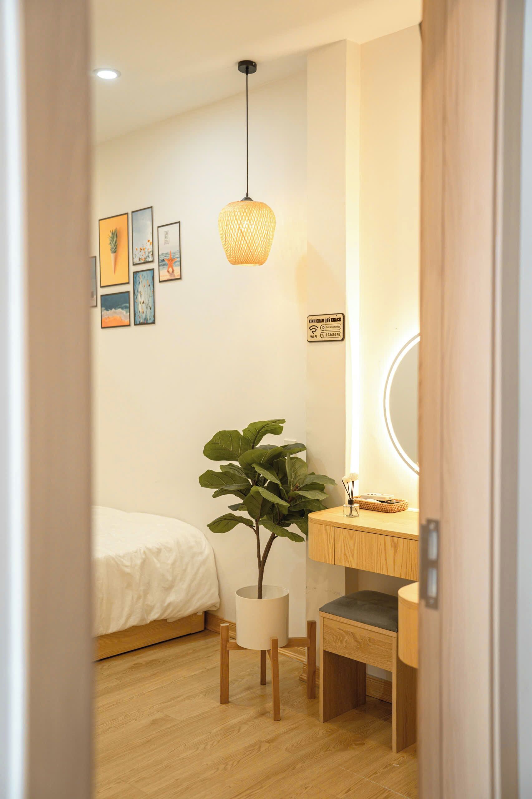 A bedroom with a bed, a bedside table, a plant, and a wall-mounted mirror.
