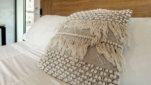 A hotel room with a bed, a wooden headboard, and an air conditioning unit mounted on the wall.