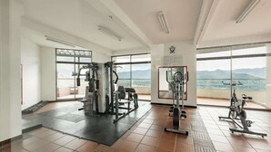 A spacious gym with exercise equipment, large windows, and a view of mountains.