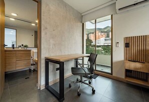 Un espace de bureau moderne comprenant un bureau, un fauteuil de bureau et une vue sur les bâtiments à travers de grandes fenêtres.