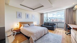 Une chambre d’hôtel moderne dotée d’un grand lit, d’un canapé, d’un bureau et offrant une vue sur la ville.