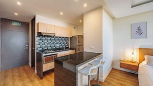 Une cuisine compacte dotée d’un îlot central, de meubles en bois et d’un pare-feu en carreaux.