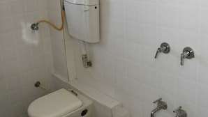 A small, tiled bathroom with a toilet, a shower, and a sink. - Hotel Nawanagar Residency (Jamnagar)