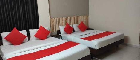 Quarto de hotel com duas camas, cada uma com roupa de cama branca e detalhes vermelhos, cabeceira com padrão listrado e cortina à esquerda.