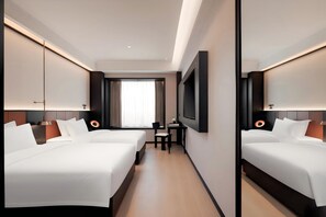 Habitación de hotel con dos camas, un escritorio, una silla, un televisor y un amplio ventanal con cortinas.