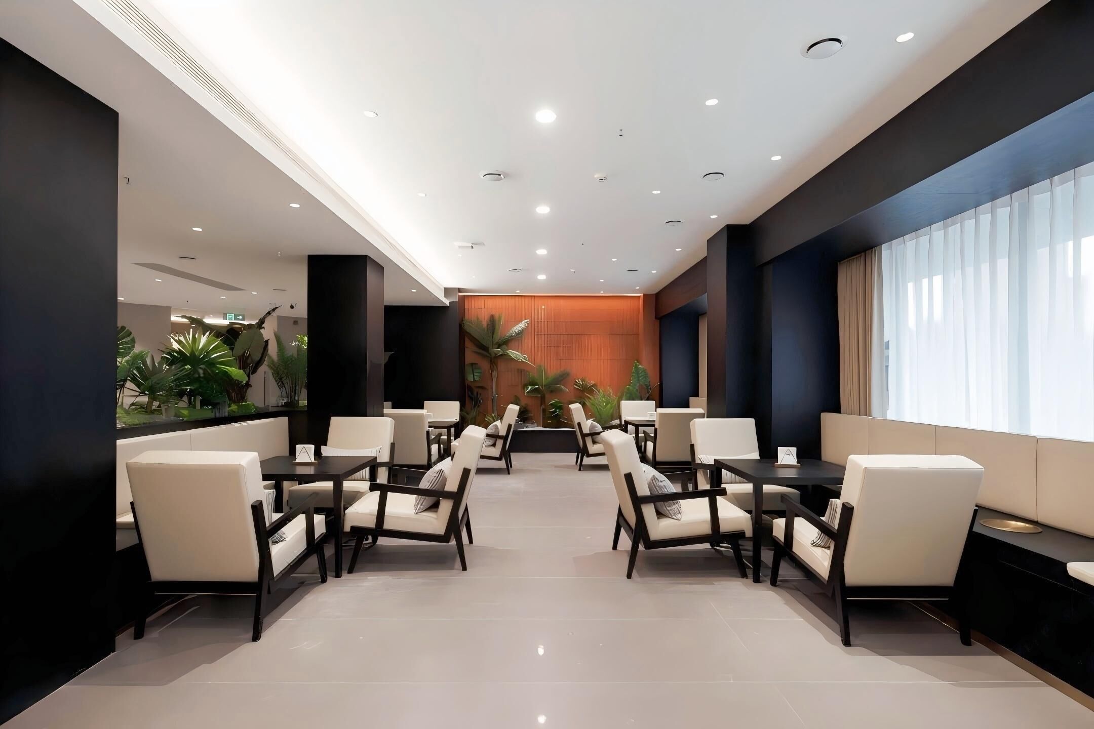 A modern hotel lobby with a central seating area, large windows, and a wooden accent wall.