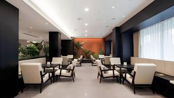 A modern hotel lobby with a central seating area, large windows, and a wooden accent wall.