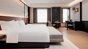 A modern hotel room with a large bed, a desk with a laptop, and a chair. - BONINGHOTEL (Meishan)