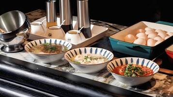 A table with various dishes, including bowls of soup and a box of eggs.