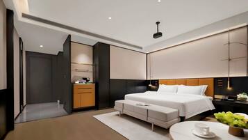 Una habitación de hotel moderna con una cama grande, mesitas de noche, un escritorio y una zona de estar.