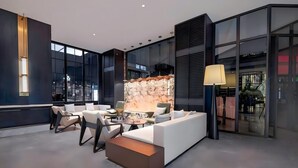A modern lounge area with a sofa, chairs, a coffee table, and a decorative wall. - BONINGHOTEL (Meishan)