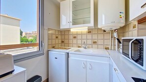 Cocina compacta con ventana, lavamanos, microondas y lavavajillas.