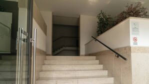 A set of marble stairs leading up to a landing with a glass door and a sign indicating a no-smoking area. - Sweet Home Daniele – appartamento in centro e ... (Lecco)