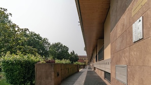 A corridor with stone flooring, a wooden ceiling, and a wall with ventilation grilles. - Sweet Home Daniele – appartamento in centro e ... (Lecco)