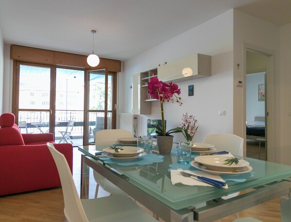 Een moderne eethoek met een glazen tafel voor vier personen, omringd door witte stoelen.