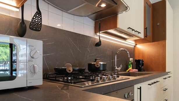 A modern kitchen with a gas stove, a microwave, and a coffee machine. - Sweet Home Daniele – appartamento in centro e ... (Lecco)