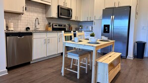 Una cocina moderna con armarios blancos, electrodomésticos de acero inoxidable y una mesa de madera con sillas.
