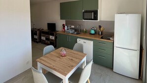 Una cocina moderna con gabinetes verdes, microondas y lavavajillas. Hay una mesa de comedor de madera con dos sillas.