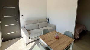 Un espacio habitable pequeño y moderno con un sofá, una mesa de madera y dos sillas.