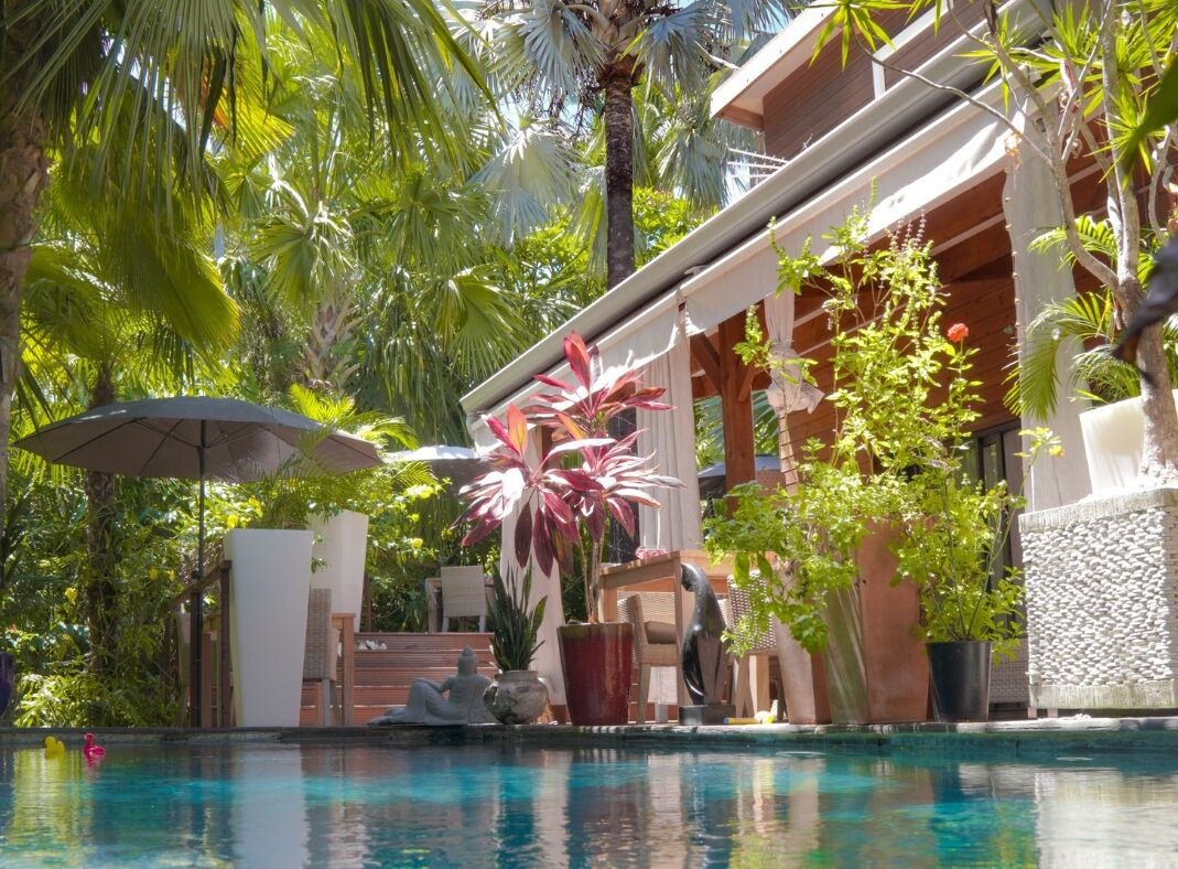 A pool area with a clear view of the pool, surrounded by lush greenery and a wooden deck.