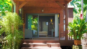A wooden porch with a bed and sliding glass doors leading to a bedroom. - Lodge Palmae (Saint-Pierre)