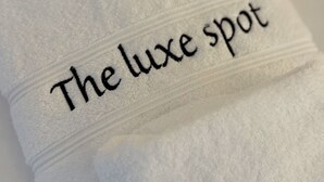 Et hvidt håndklæde med broderet tekst: "The luxe spot".