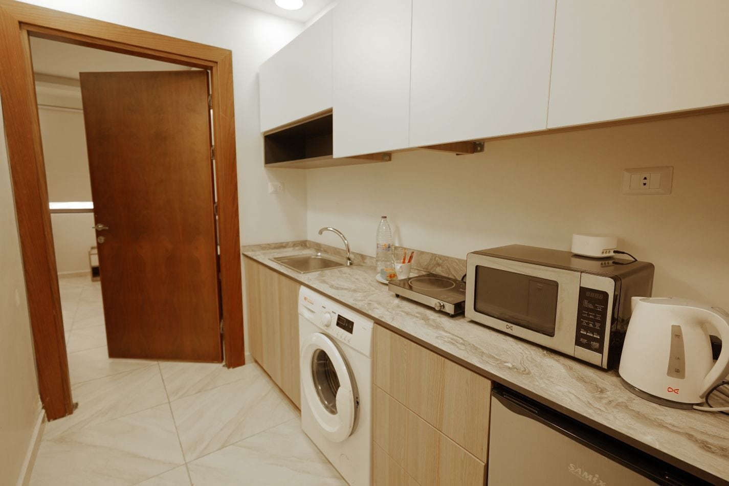 A compact kitchen with a washing machine, microwave, and coffee maker.