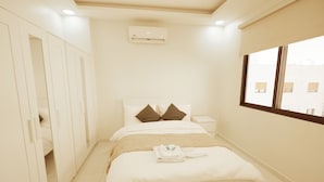Ein Hotelzimmer mit Bett, Nachttischen, einer Klimaanlage und einem Fenster mit Jalousien.